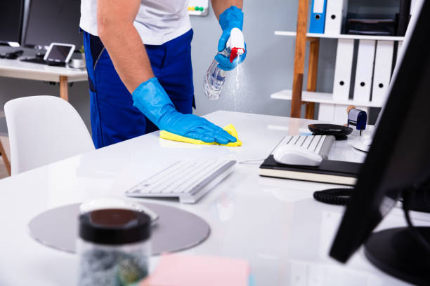 Janitor cleaning white desk in modern office